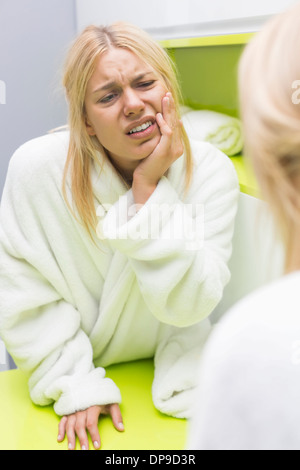 Giovane donna che soffre di mal di denti mentre guardando lo specchio Foto Stock