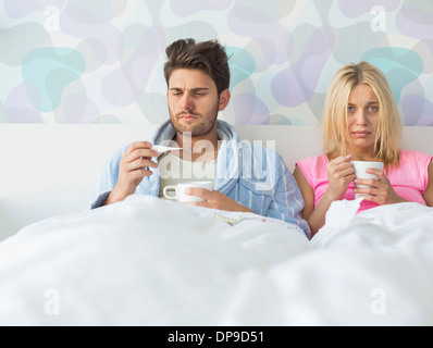 Triste giovane azienda tazze da caffè mentre vi rilassate sul letto Foto Stock