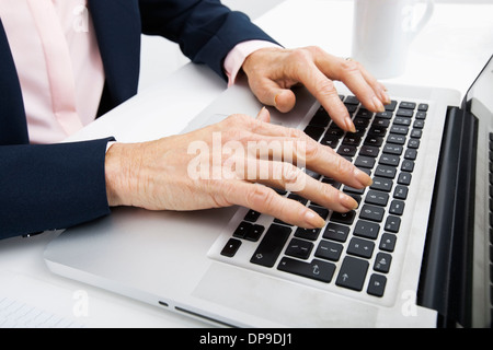 Immagine ritagliata di senior imprenditrice digitando su laptop Foto Stock