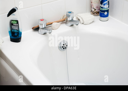 Il riempimento di una vasca da bagno con acqua sporca da acceso a caldo e a freddo di rubinetti Foto Stock