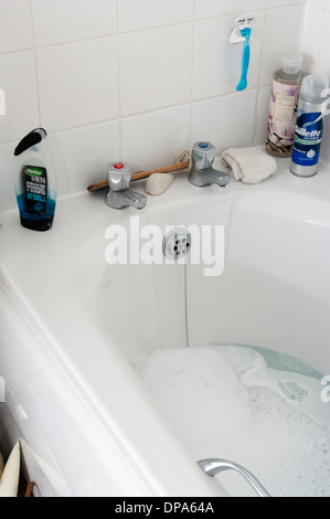 Il riempimento di una vasca da bagno con acqua sporca da acceso a caldo e a freddo di rubinetti Foto Stock