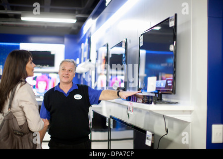 Donna che guarda la TV a schermo piatto in showroom Foto Stock