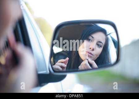 Giovane donna rossetto in specchio auto Foto Stock