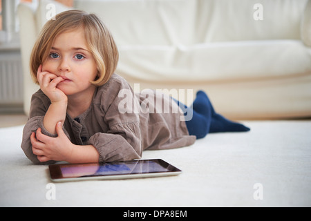 Ragazza distesa sul pavimento con tavoletta digitale Foto Stock