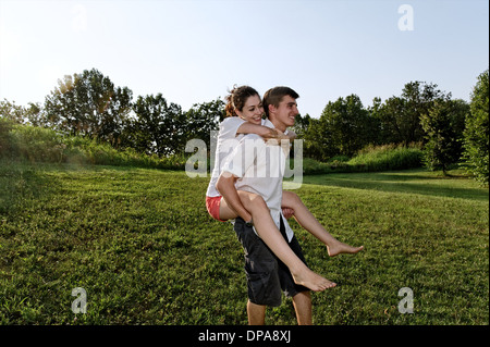 Giovane uomo dando piggyback ride di giovane donna Foto Stock