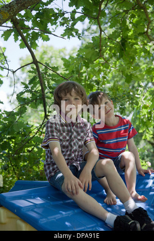 Ragazzi seduti sul tetto di casa ad albero Foto Stock