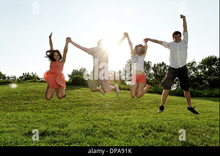 Un gruppo di giovani adulti jumping metà aria nel campo Foto Stock