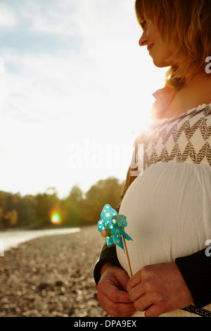 Donna incinta in piedi accanto al fiume il mulino a vento di contenimento Foto Stock