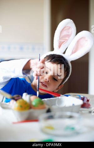 Ragazzo indossa orecchie di coniglietto di pittura delle uova di Pasqua Foto Stock