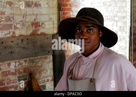 Rienattore dell'epoca della guerra civile afroamericana a ft. Delaware si pone nel lavoro del fabbro, indossando il costume d'epoca di un apprendista del fabbro. Foto Stock