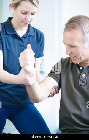 Fisioterapista aiutare l uomo a fare esercizio del braccio Foto Stock