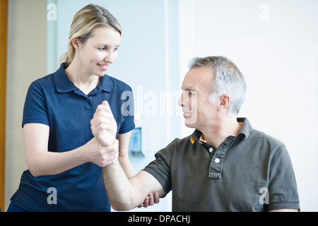 Fisioterapista aiutare l uomo a fare esercizio del braccio Foto Stock