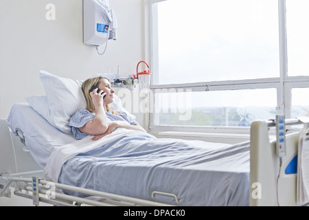 Paziente sdraiato sul letto di ospedale su chiamata telefonica Foto Stock