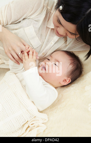 La madre e il bambino giacente insieme tenendo le mani Foto Stock