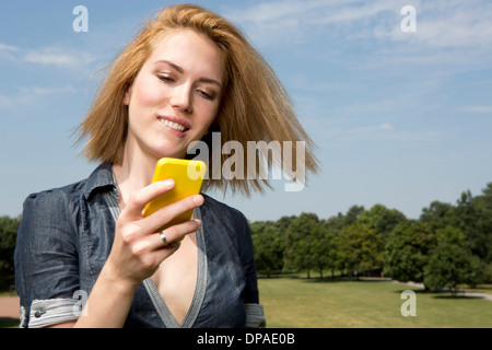 Giovane donna utilizza lo smartphone in posizione di parcheggio Foto Stock