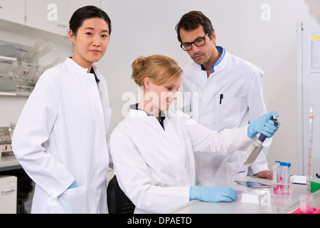 Gruppo di scienziati test in laboratorio, soluzione di pipettaggio Foto Stock
