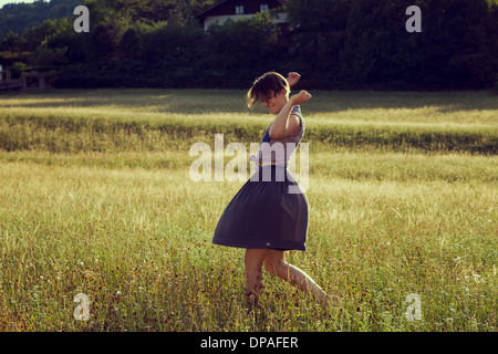 Giovane donna a piedi attraverso Prato Foto Stock