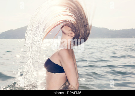 Giovane donna in mare di gettare la testa indietro Foto Stock