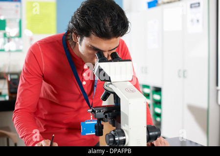 Studente di chimica mediante microscopio in laboratorio Foto Stock