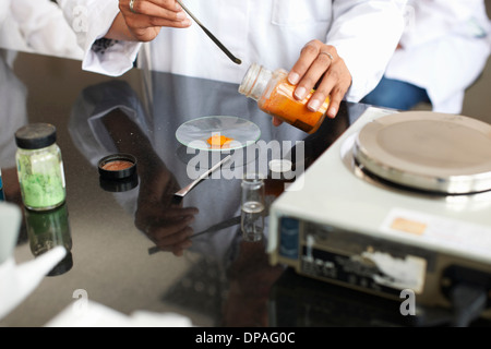 Tecnico di sesso femminile del peso di sostanze chimiche in laboratorio Foto Stock