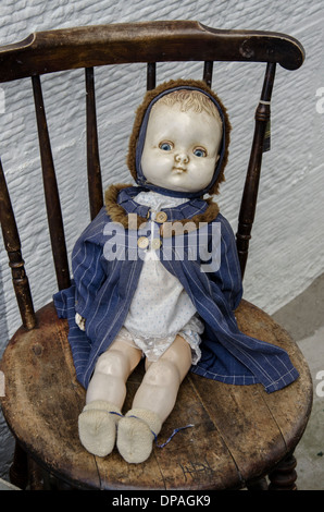 Vintage del bambino bambola seduta su una vecchia sedia al di fuori di un negozio di posta indesiderata a Edimburgo, Scozia. Foto Stock