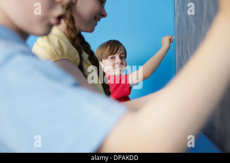 Bambini scrivere sulla lavagna, sfondo blu Foto Stock