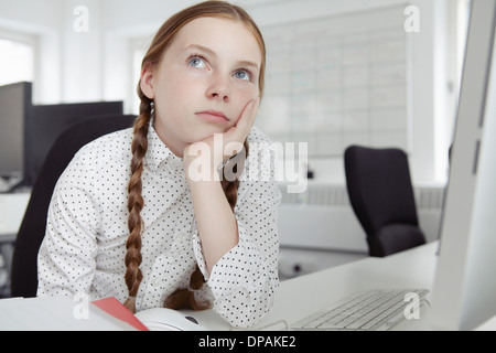 La ragazza con la mano sul mento cercando in office Foto Stock