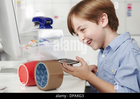 Ragazzo giocando con le apparecchiature per ufficio Foto Stock