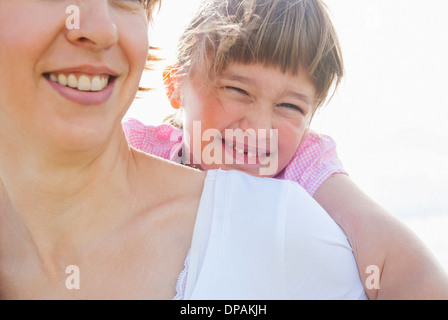 Madre dando figlia piggy back Foto Stock