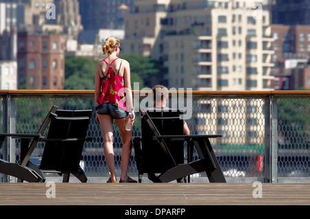 Una giovane coppia in Lower Manhattan guarda gli edifici Brooklyn Heights in una giornata estiva brillante. Foto Stock