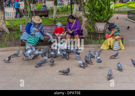 Tre donne e un bambino che alimenta i piccioni nella centrale Plaza, 25 Plaza de Mayo, in Sucre, Bolivia. Foto Stock