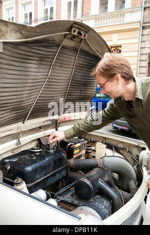 L'uomo controlli di livello carburante mediante l'astina di livello nel serbatoio (nessun carburante gage) nella sua Trabant vettura Foto Stock