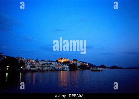 Una vista sul lago Pichola al City Palace di Udaipur in Rajasthan in India in Asia del Sud. Sunset Blue Sky Travel crepuscolo crepuscolo Wanderlust Foto Stock