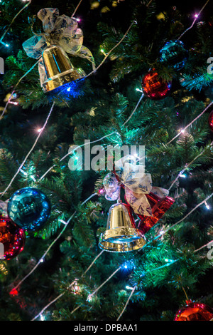 Una chiusura di decorazioni di Natale, ornamenti e luci su un albero di Natale. Foto Stock