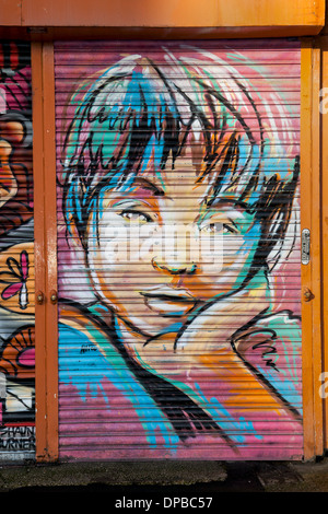 Graffit verniciatura a spruzzo sulla serranda metallica nel quartiere nord N4 o NQ 2, il centro città di Manchester, Inghilterra, Regno Unito Foto Stock