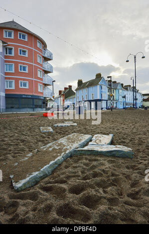 Aberystwyth, Wales, Regno Unito. Il 10 gennaio 2014. Una settimana dopo una violenta tempesta a sovracorrenti e gale force venti danneggiato Aberystwyth sul lungomare, detriti è ancora sparsi intorno alla zona. I lavoratori del consiglio di grado i depositi di alluvione con macchine per separare la sabbia e la pavimentazione in lastre. Lavoro inizia lo smantellamento del grado 2 elencati rifugio pubblico, le cui fondamenta sono stati compromessi dal mare. Credito: keith burdett/Alamy Live News Foto Stock