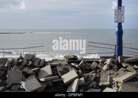 Aberystwyth, Wales, Regno Unito. Il 10 gennaio 2014. Una settimana dopo una violenta tempesta a sovracorrenti e gale force venti danneggiato Aberystwyth sul lungomare, detriti è ancora sparsi intorno alla zona. I lavoratori del consiglio di grado i depositi di alluvione con macchine per separare la sabbia e la pavimentazione in lastre. Lavoro inizia lo smantellamento del grado 2 elencati rifugio pubblico, le cui fondamenta sono stati compromessi dal mare. Credito: keith burdett/Alamy Live News Foto Stock