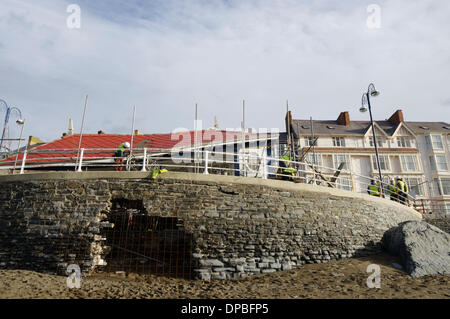 Aberystwyth, Wales, Regno Unito. Il 10 gennaio 2014. Una settimana dopo una violenta tempesta a sovracorrenti e gale force venti danneggiato Aberystwyth sul lungomare, detriti è ancora sparsi intorno alla zona. I lavoratori del consiglio di grado i depositi di alluvione con macchine per separare la sabbia e la pavimentazione in lastre. Lavoro inizia lo smantellamento del grado 2 elencati rifugio pubblico, il Minato le fondazioni di cui ha precedentemente conteneva un capanno in stile vittoriano e, ripetutamente, il sito della città patibolo. Credito: keith burdett/Alamy Live News Foto Stock