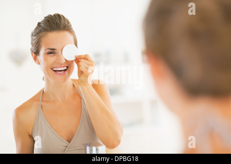 Giovane donna utilizzando con tampone di cotone nella stanza da bagno Foto Stock