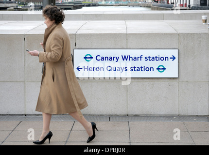 Londra, Inghilterra, Regno Unito. Docklands / Canary Wharf. Segno di dare le indicazioni per la stazione della metropolitana e Heron Quays Foto Stock