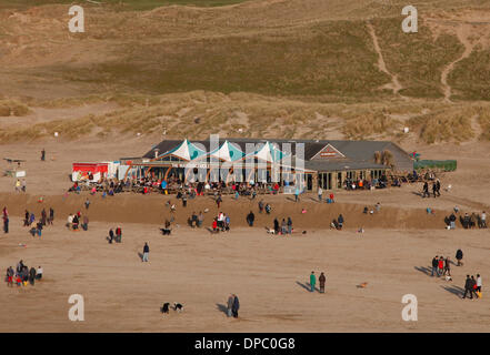 Perranporth, Cornwall, Regno Unito. 11 gennaio 2014. Il Watering Hole bar sulla spiaggia è a soli pochi metri dall'essere lavato via da ultima settimana di enormi tempeste che lefit è arroccato su un 3 metro di altezza ripiano. La folla fare più di una giornata di sole sulla spiaggia. Credito: Anthony Collins/Alamy Live News Foto Stock