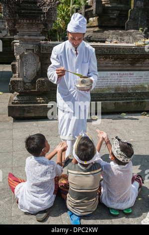 Bambini pregano presso Tirta Empul temple, Bali, Indonesia, in Asia. Foto Stock