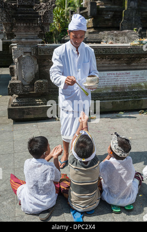 Bambini pregano presso Tirta Empul temple, Bali, Indonesia, in Asia. Foto Stock