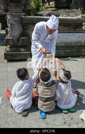 Bambini pregano presso Tirta Empul temple, Bali, Indonesia, in Asia. Foto Stock