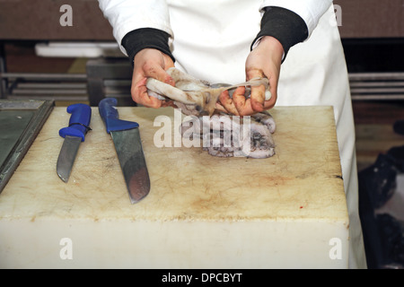 Un lavoratore la pulizia di un polpo fresco nel tuo pescivendolo Foto Stock