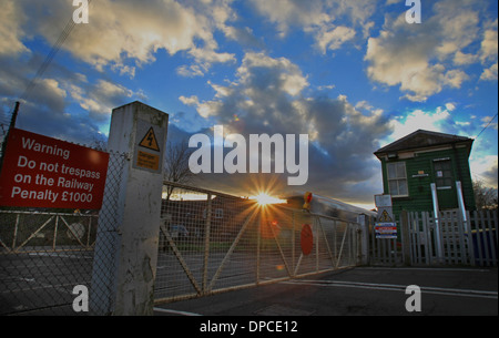 Un Sud Orientale treno passeggeri passa un segnale rifugio al tramonto con ferrovie segnaletica di avvertimento al passaggio a livello Chartham, Kent Foto Stock