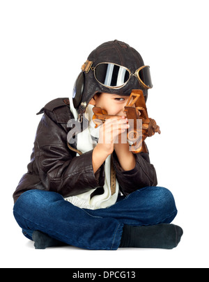 Felice ragazzo carino vestita come una guerra mondiale II riproduzione pilota con legno giocattolo aereo su sfondo bianco.look vintage Foto Stock