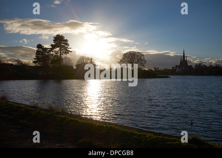 Inverno il sole tramontare sull'orizzonte di Stowe in piscina a Lichfield city centre Foto Stock