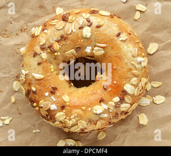 Multi-grano bagel coperto di avena e semi zigrinato sulla carta marrone Foto Stock