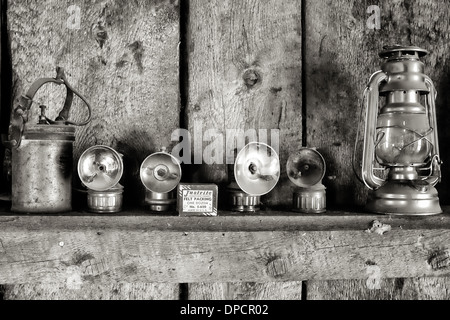 Lampade e lanterne su un ripiano con feltro di in un vecchio rustico cabina Foto Stock